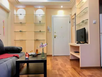 a living room with a couch and a table and a tv at A2 Cute Vouliagmeni Apt in a Unique Spot in Athens