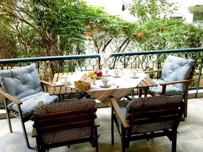 a wooden table and chairs on a balcony with a meal on it at A2 Cute Vouliagmeni Apt in a Unique Spot in Athens