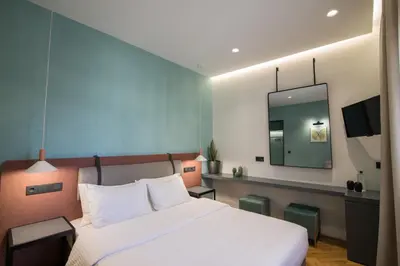a bedroom with a white bed and a mirror at Ederlezi Zoubourlou Aparthotel in Athens