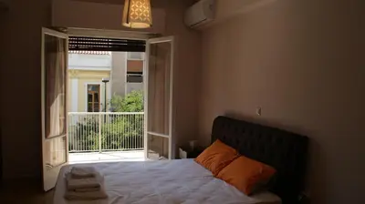 a bedroom with a bed and an open window at The Victoria Square Exceptional Apartments in Athens