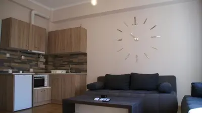 a living room with a couch and a clock on the wall at The Victoria Square Exceptional Apartments in Athens