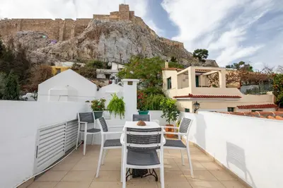 a terrace with a table and chairs with a view of the mountain at In the shadow of Acropolis in Athens