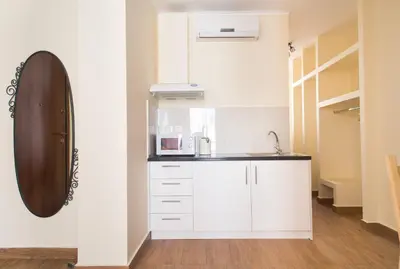 a white kitchen with a sink and a mirror at Syntegma studio next to Ermou street in Athens
