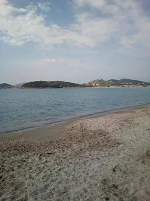 a beach with the ocean and houses in the distance at Family and friendly home. in Palaiá Fókaia