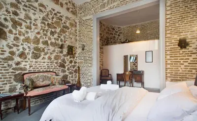 a bedroom with a stone wall and two beds at A litte Taste of Home Guest House in Athens