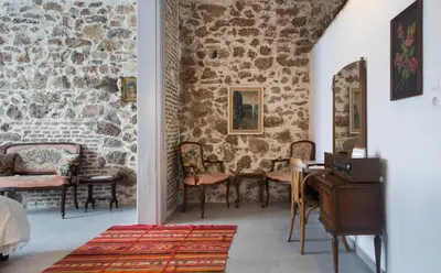 a room with chairs and a stone wall at A litte Taste of Home Guest House in Athens
