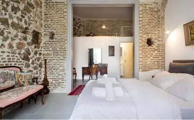 a bedroom with a white bed and a brick wall at A litte Taste of Home Guest House in Athens