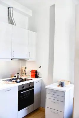 a kitchen with white cabinets and a black stove top oven at Erst Guest House in Athens