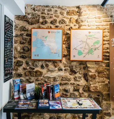 a table against a stone wall with maps and books at Athens Hub Hostel in Athens