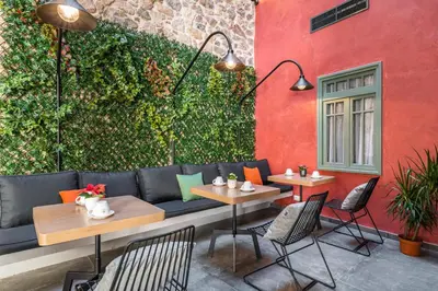 a patio with tables and chairs and a green wall at Athens Hub Hostel in Athens