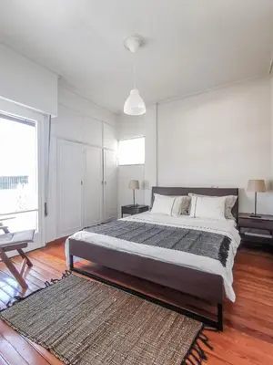a white bedroom with a large bed and a rug at Acropolitana Grand view veranda in Athens