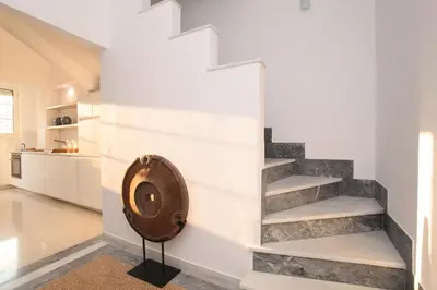 a staircase in a living room with white walls and a wooden wheel at Plaka Two-Storey Penhouse with Acropolis Views PL6 in Athens