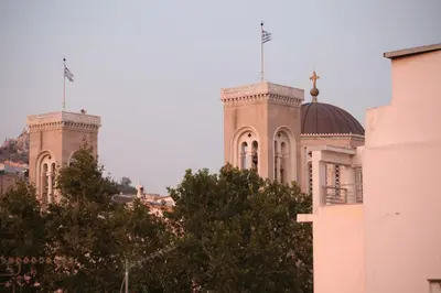 a building with two towers with trees in the foreground at Plaka Two-Storey Penhouse with Acropolis Views PL6 in Athens
