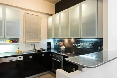 a kitchen with black counters and white cabinets at Stylish flat with veranda in the heart of Athens in Athens