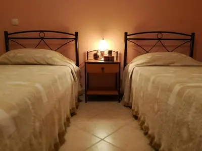a bedroom with two beds and a nightstand with a lamp at Platos Academy Apartment in Athens