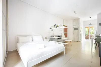 a white bedroom with a white bed and a table at Cozy Studio in Central Glyfada in Athens