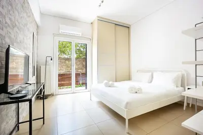 a white bedroom with a bed and a window at Cozy Studio in Central Glyfada in Athens