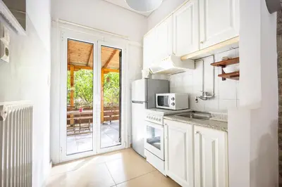 a kitchen with white cabinets and a large window at Cozy Studio in Central Glyfada in Athens