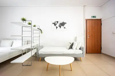 a living room with two beds and a table at Cozy Studio in Central Glyfada in Athens
