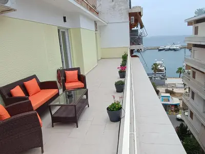 a balcony with chairs and a glass table on a building at Uncle Tom's Penthouse in Piraeus