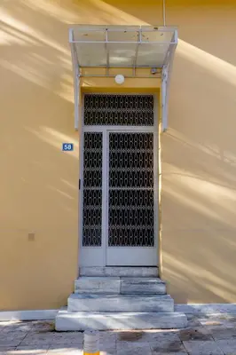 a door with a metal grill on a yellow building at Troon of Athens Apartments in Athens