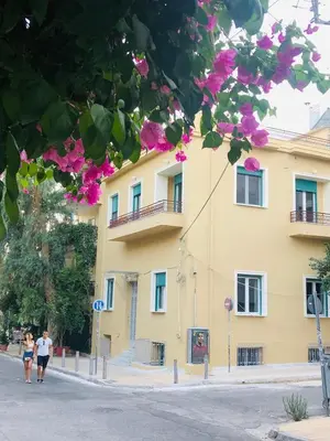 two people walking in front of a yellow building at Troon of Athens Apartments in Athens