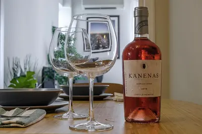 a bottle of wine next to two glasses on a table at Photographers House in Athens