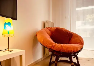 an orange chair sitting in a room next to a lamp at Elenis Athens Apartment in Athens