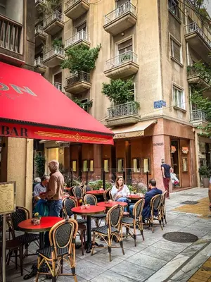 a group of people sitting at tables outside a restaurant at API Projects Athens - Cartier Apartment in Athens