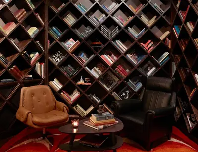 a library with a chair and a table and books at Brown Acropol, a member of Brown Hotels in Athens