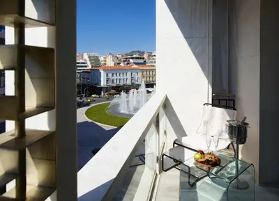 a balcony with a bowl of fruit and a view of a fountain at Brown Acropol, a member of Brown Hotels in Athens