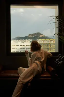 a woman sitting on a bench looking out a window at Brown Acropol, a member of Brown Hotels in Athens