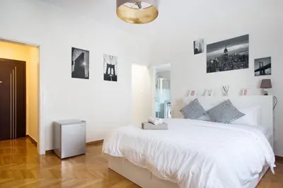 a white bedroom with a white bed and pictures on the wall at Syntagma Rita apartment 2 in Athens