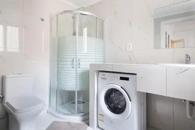 a white bathroom with a washing machine in it at Syntagma Rita apartment 2 in Athens