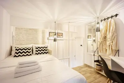 a white bedroom with a white bed and a sink at Acropolis Elegant Maisonette by LODGESPOT in Athens