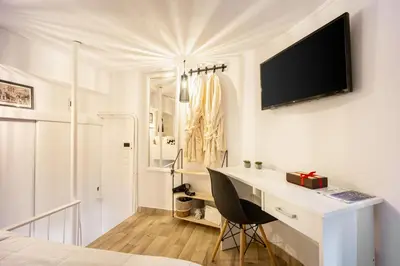 a white bedroom with a desk and a tv on the wall at Acropolis Elegant Maisonette by LODGESPOT in Athens