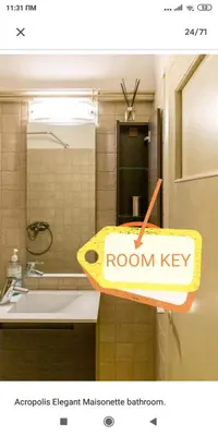 a bathroom with a room key sign on a sink at Acropolis Elegant Maisonette by LODGESPOT in Athens