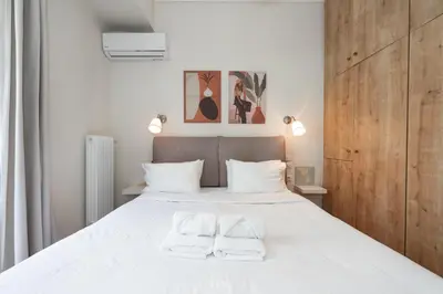 a bedroom with a large white bed with two white towels at Contemporary apartment made of wood and stone. in Athens