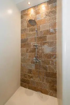 a bathroom with a shower with a brick wall at Contemporary apartment made of wood and stone. in Athens