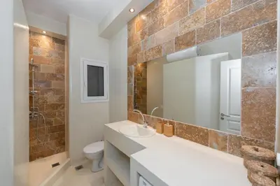 a bathroom with a sink and a toilet and a mirror at Contemporary apartment made of wood and stone. in Athens