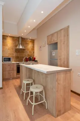 a kitchen with a large island with two stools at Contemporary apartment made of wood and stone. in Athens