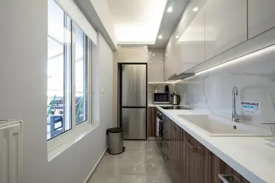 a white kitchen with a sink and a window at Trojan Affair Residence in Athens