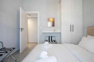 a white bedroom with a bed with towels on it at Trojan Affair Residence in Athens