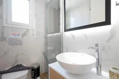 a white bathroom with a sink and a mirror at Trojan Affair Residence in Athens
