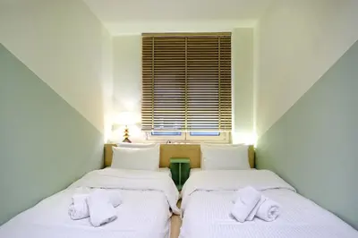 two twin beds in a room with a window at The Fancy Philosopher Apartment in Athens