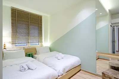 two beds in a room with a window at The Fancy Philosopher Apartment in Athens