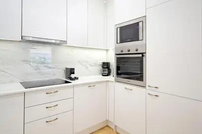 a white kitchen with white cabinets and a microwave at The Fancy Philosopher Apartment in Athens