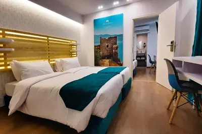 a hotel room with a large bed and a table at Athenian Montaza Hotel in Athens
