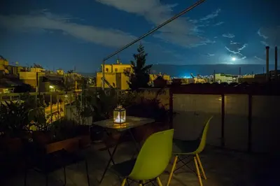 a table and chairs on a balcony at night at Sunny Top Floor Studio - Excellent Athens view in Athens
