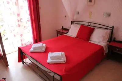 a bedroom with a red bed with two towels on it at Artemis Rooms in Agia Marina Aegina